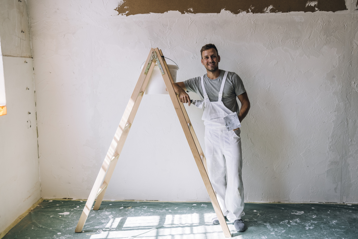 Portrait of a Smiling Young Man Plastering Wall in his Workshop